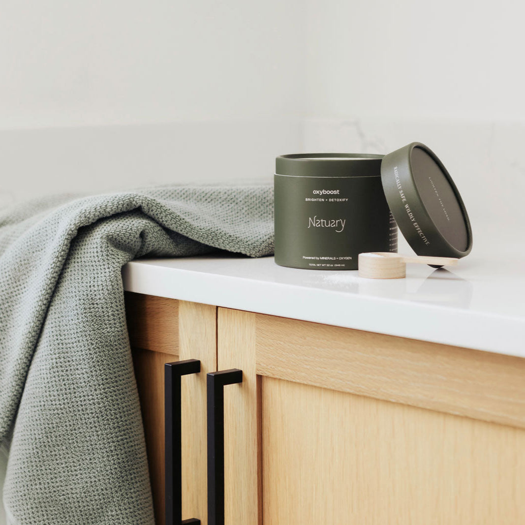 Oxyboost with a wooden scoop on a counter next to a towel