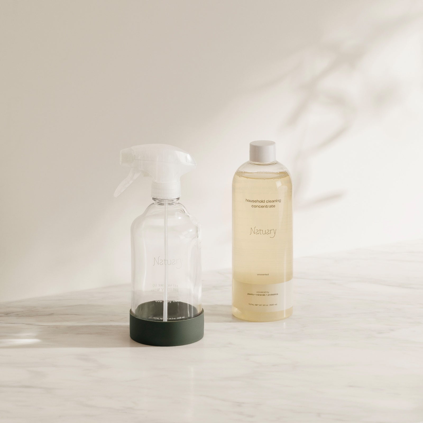 Clear glass spray bottle and Natuary cleaning concentrate on light surface.