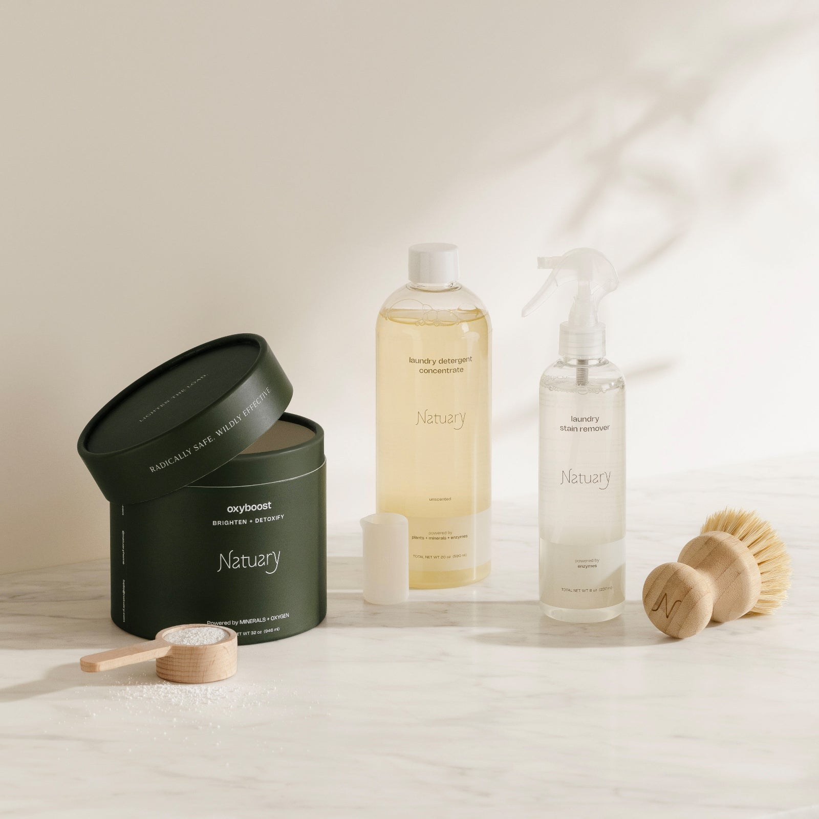 Naturally branded cleaning products including a bottle, container, and brush on a light background