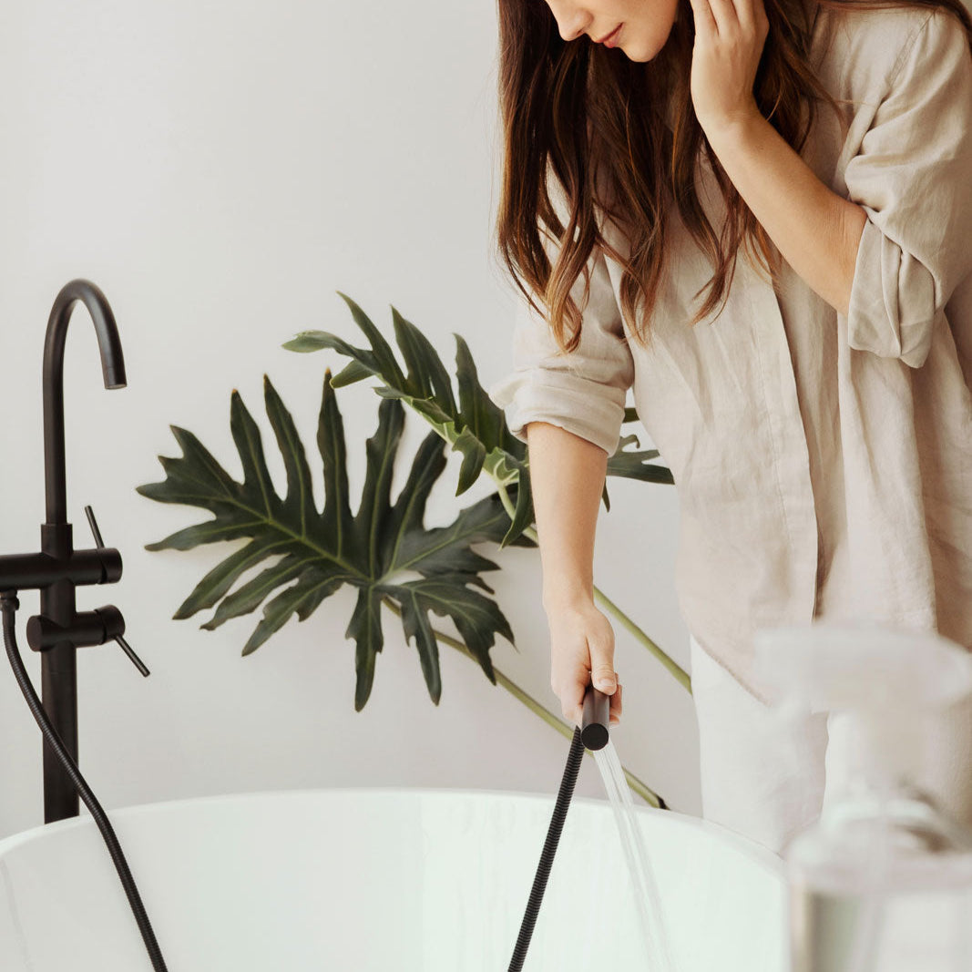 Woman watering a plant in a bathroom setting